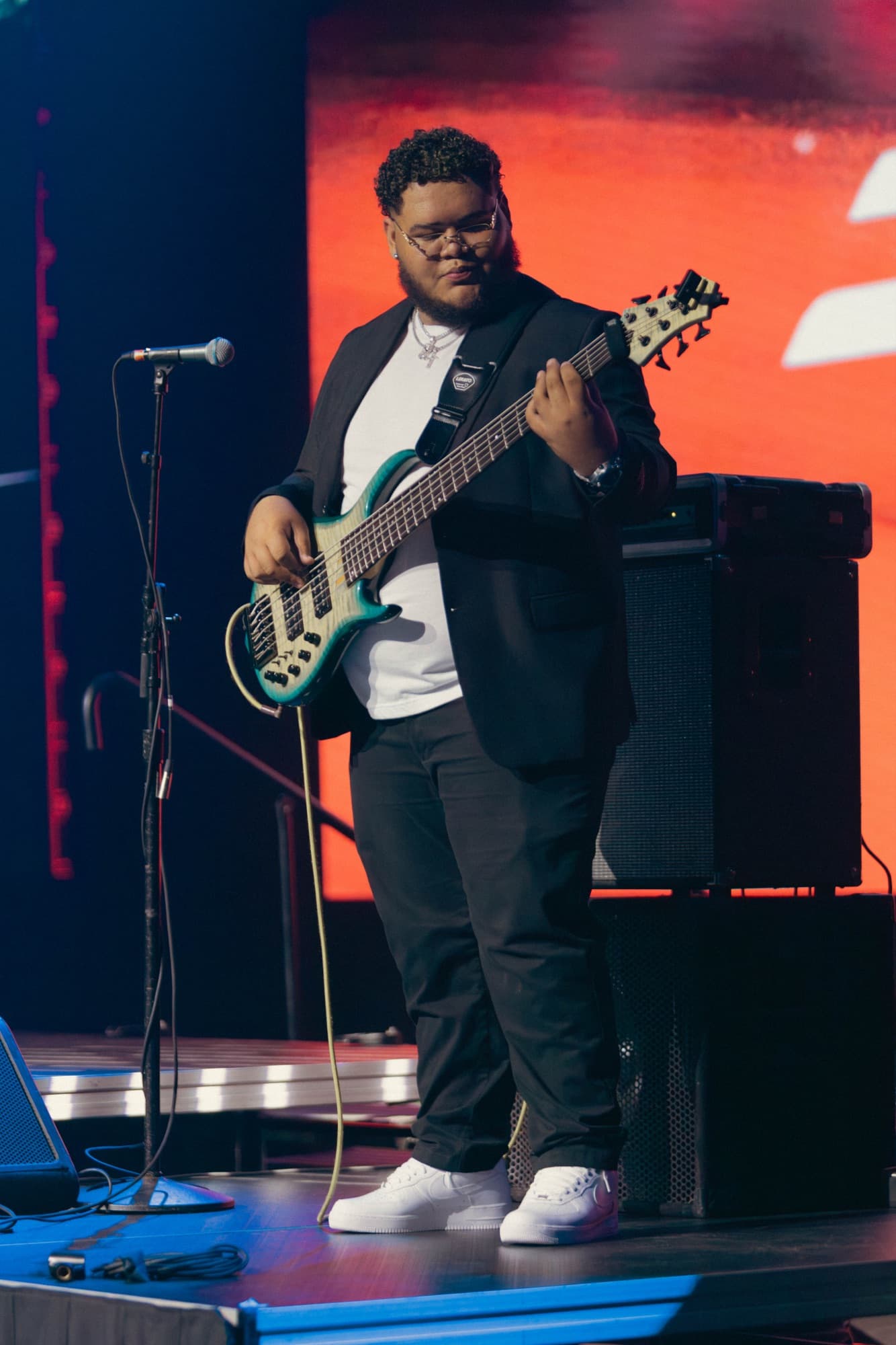 Bassist in a black suit with a teal five-string