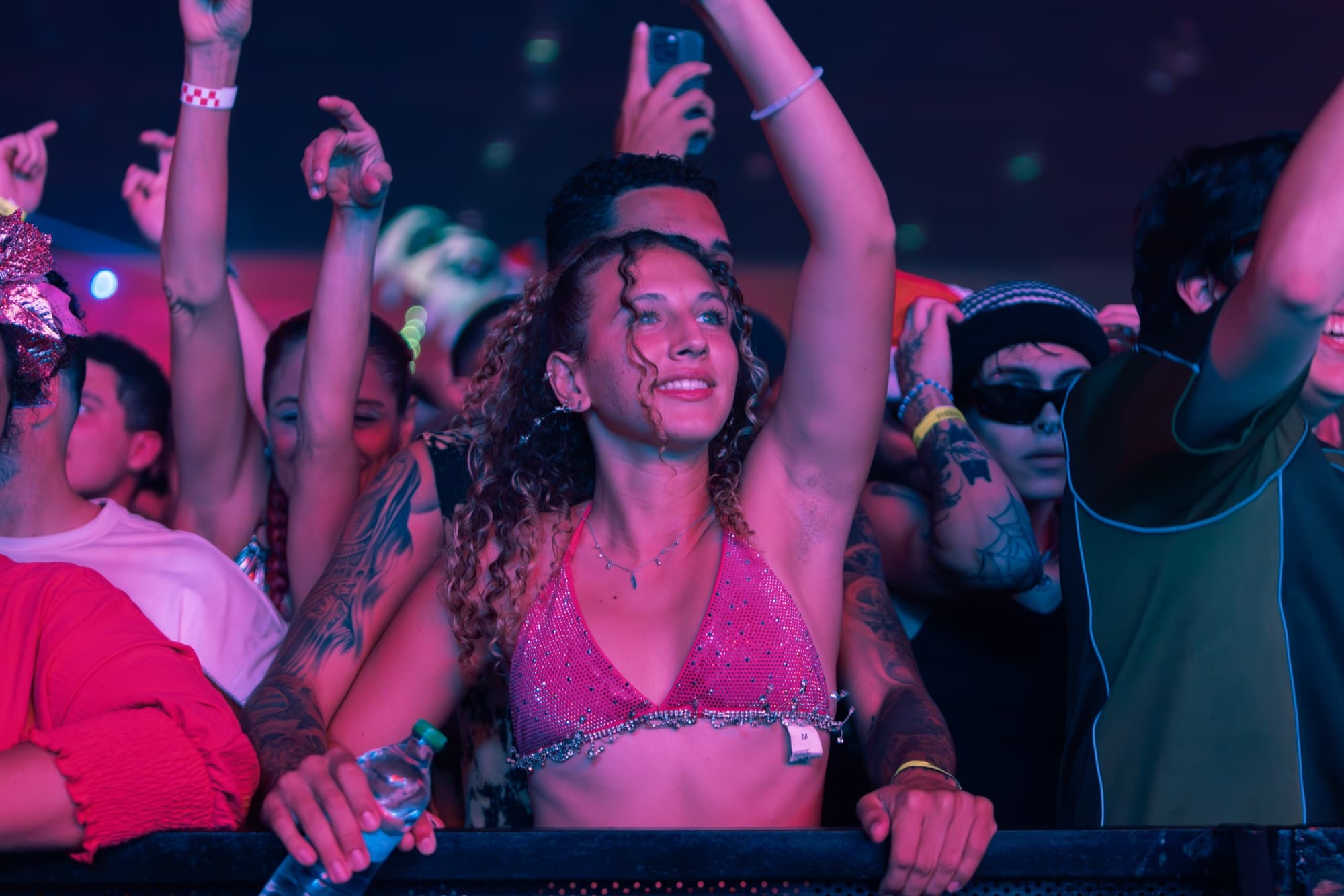 Dancer with curls in a pink sparkly top mid-crowd