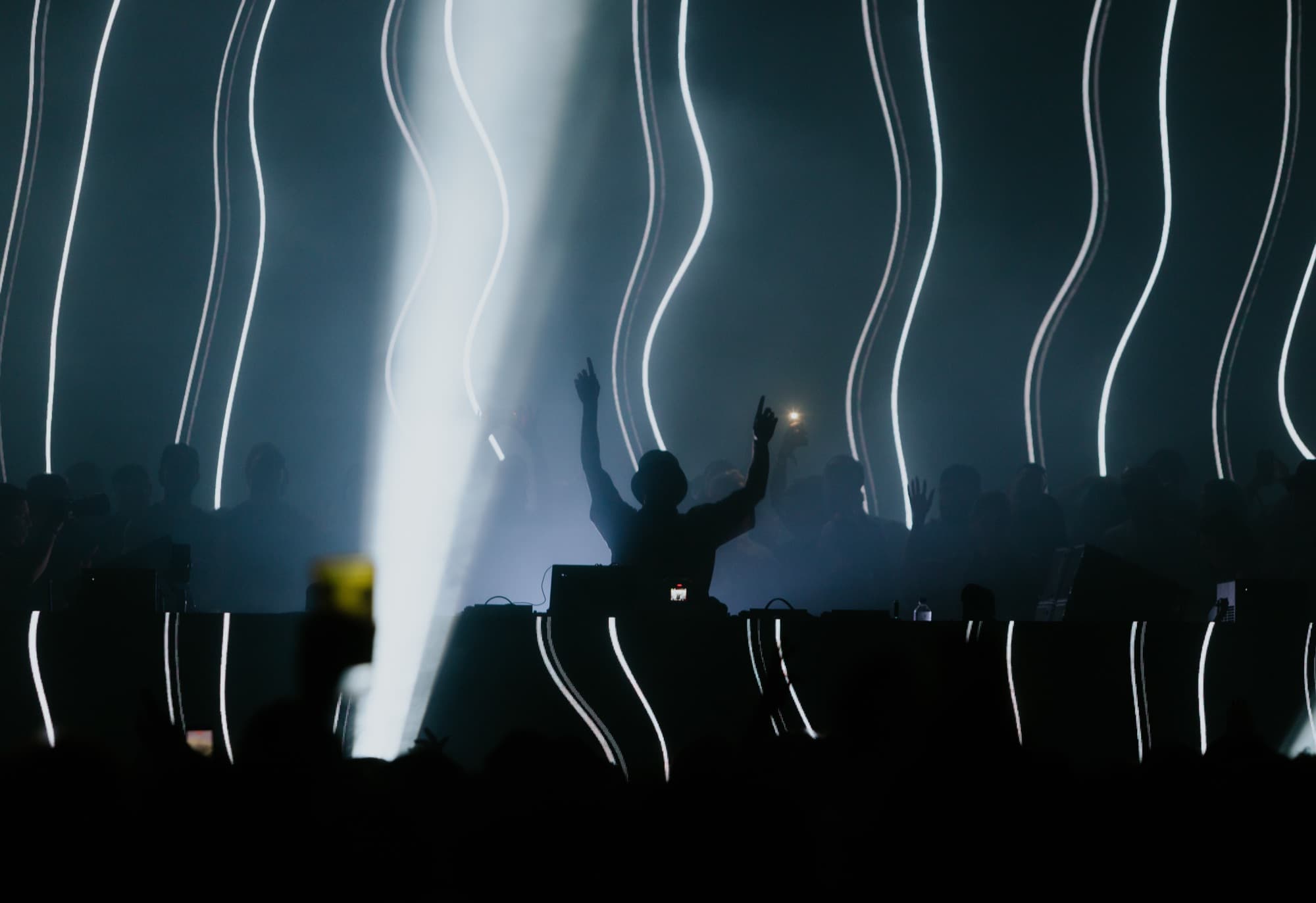 DJ silhouetted under columns of white strobes