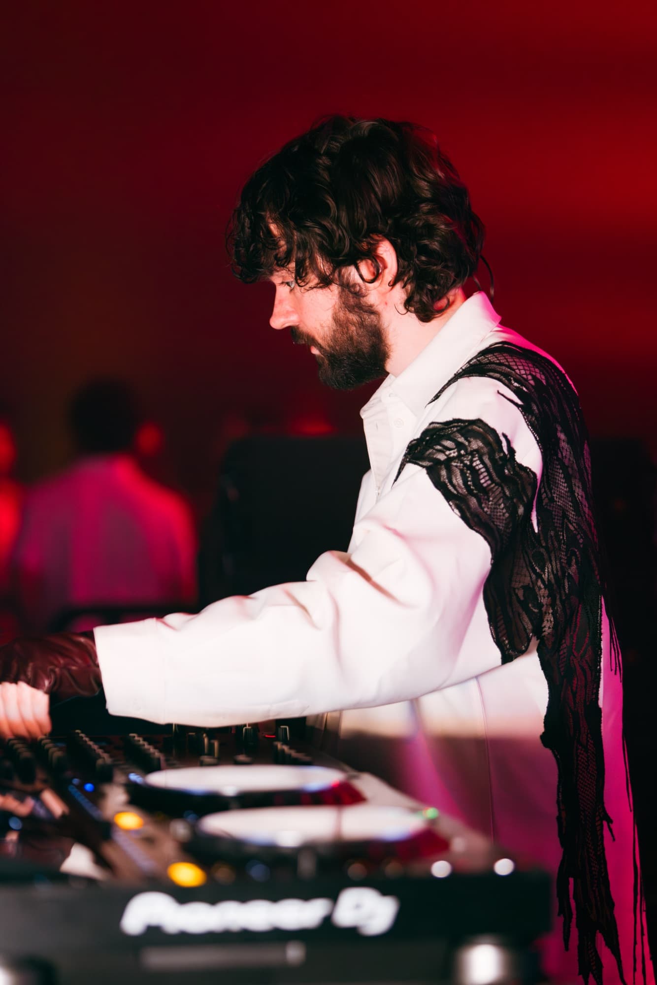 DJ in a white jacket with lace sleeves under red light