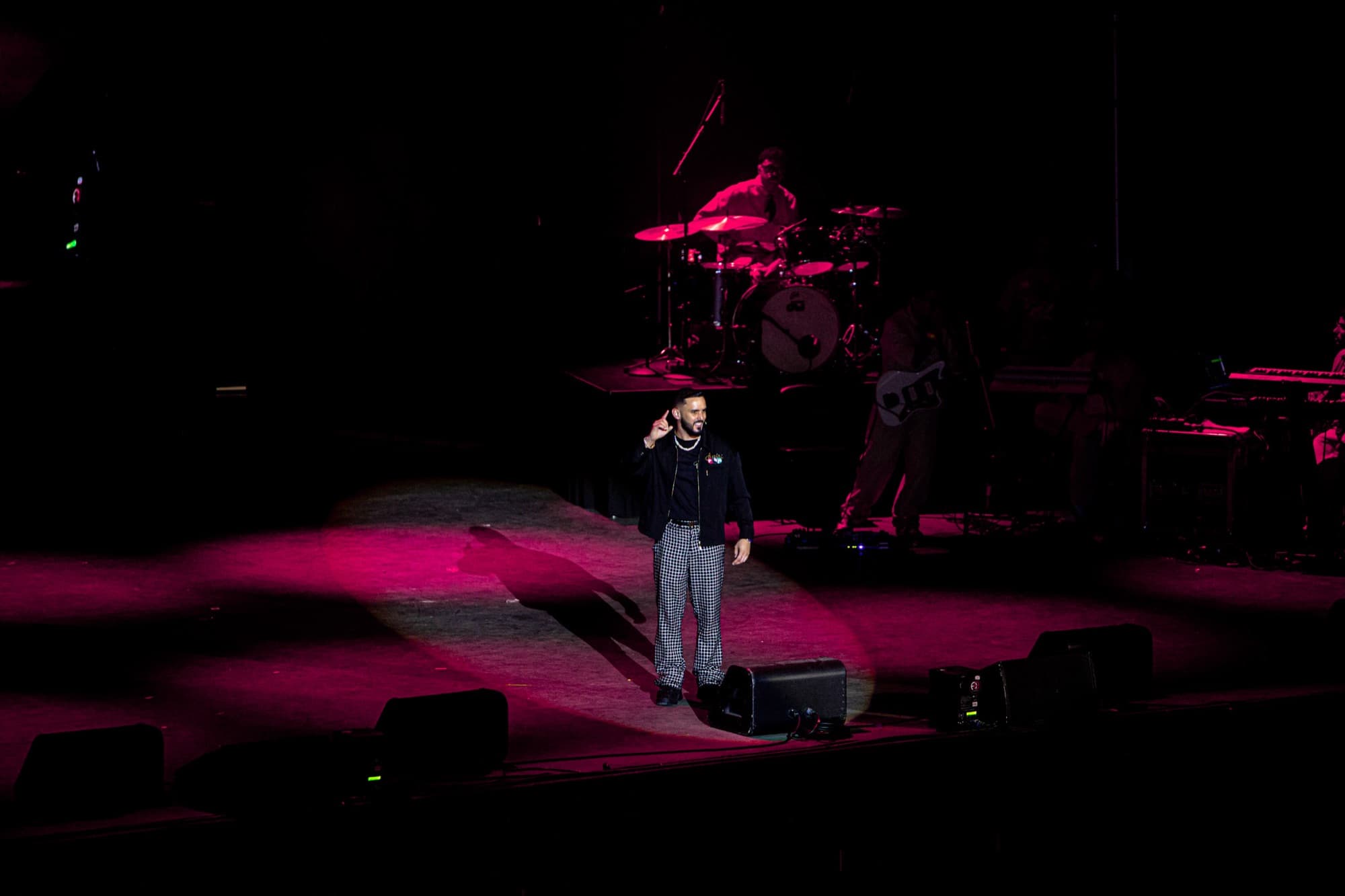 Elías alone in the spotlight on a magenta-lit stage
