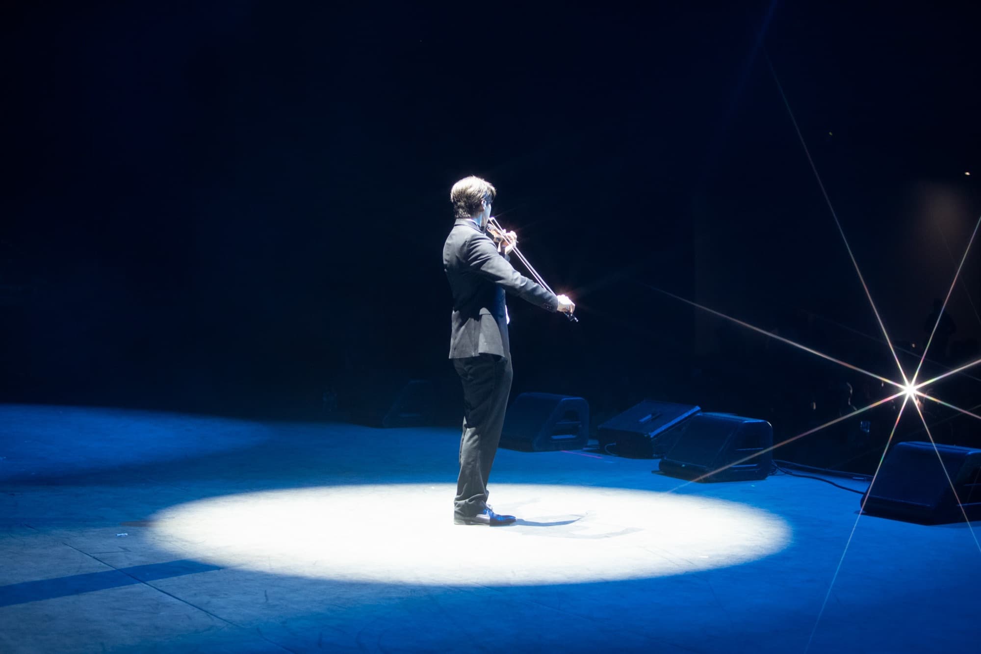 Violinist in a suit playing in a white spotlight
