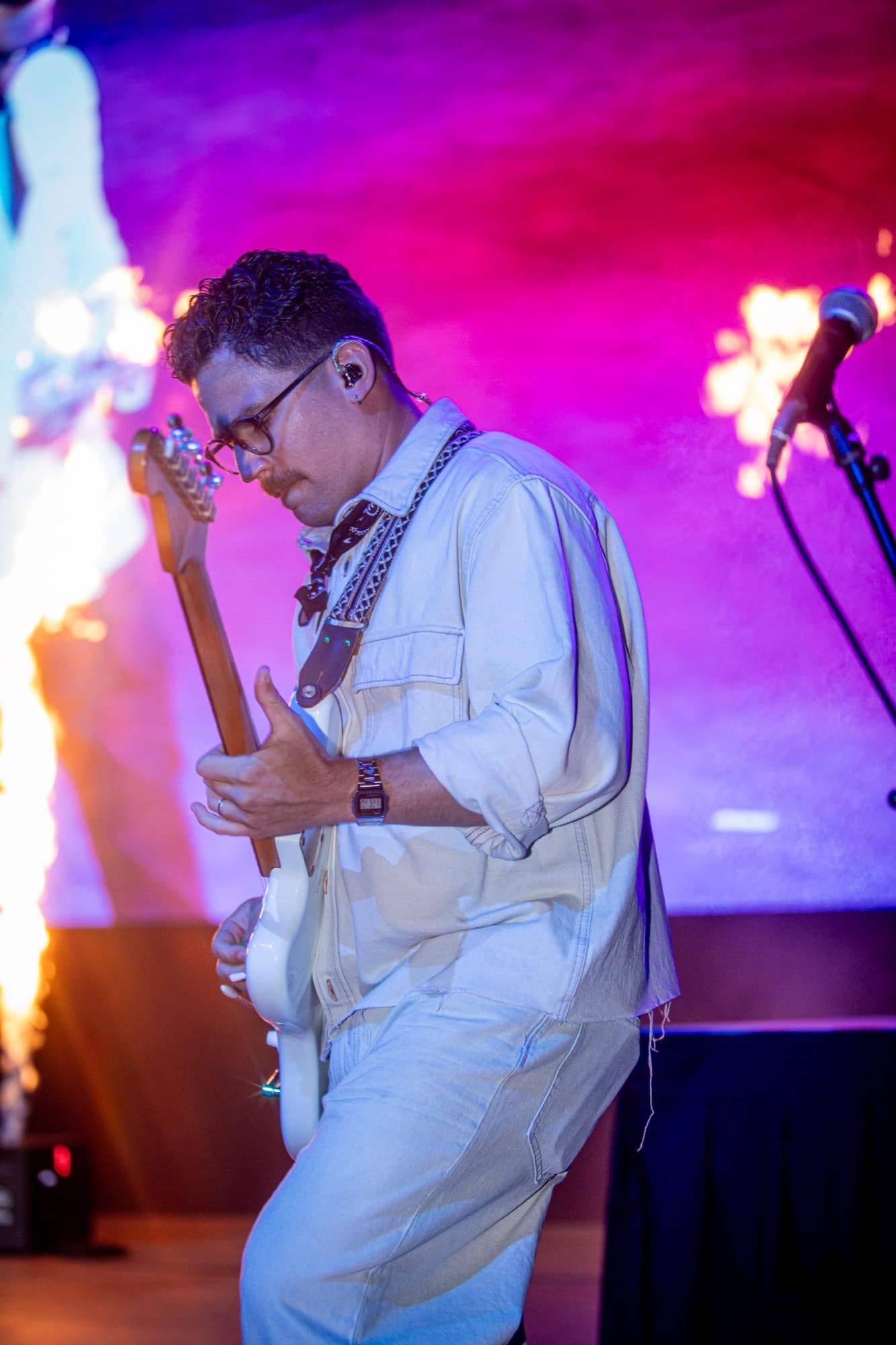 Guitarist in cream glowing under pink light