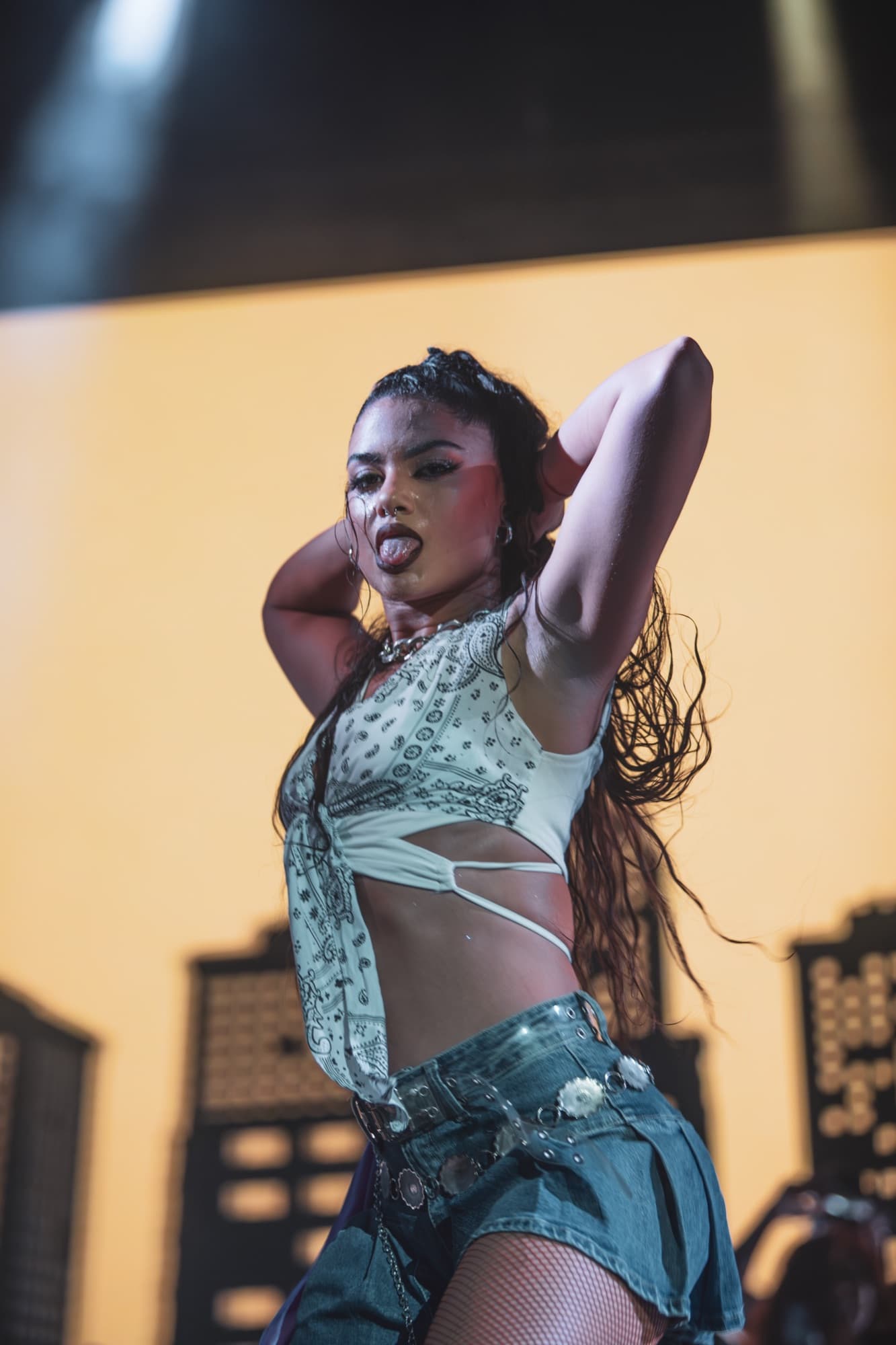 Dancer in a bandana-print set with arms raised against golden light