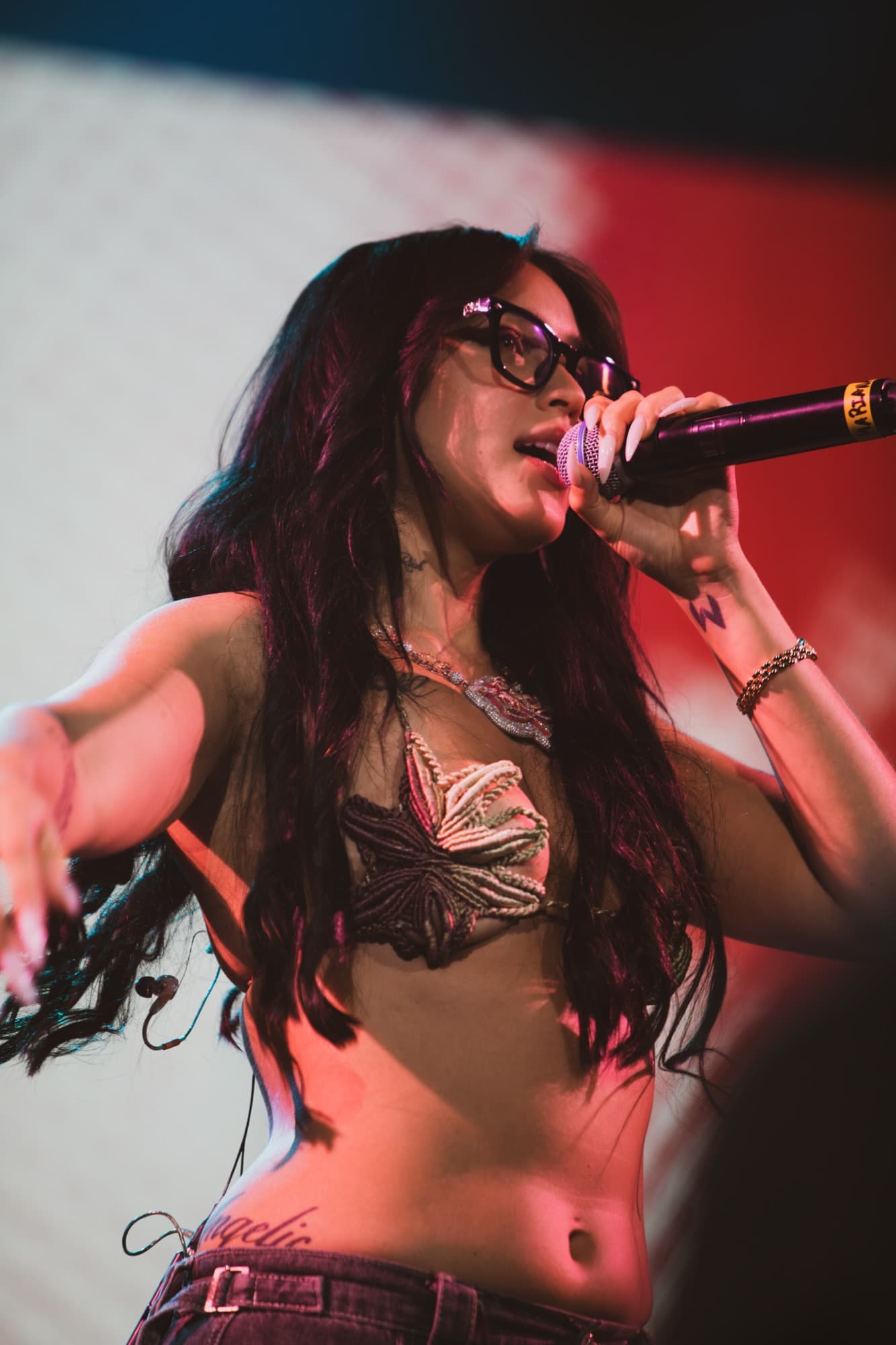 Singer with long dark hair performing under red light