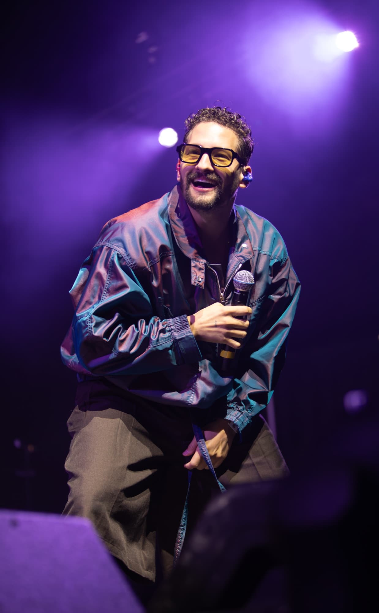 Guaynaa smiling mid-song under warm stage light