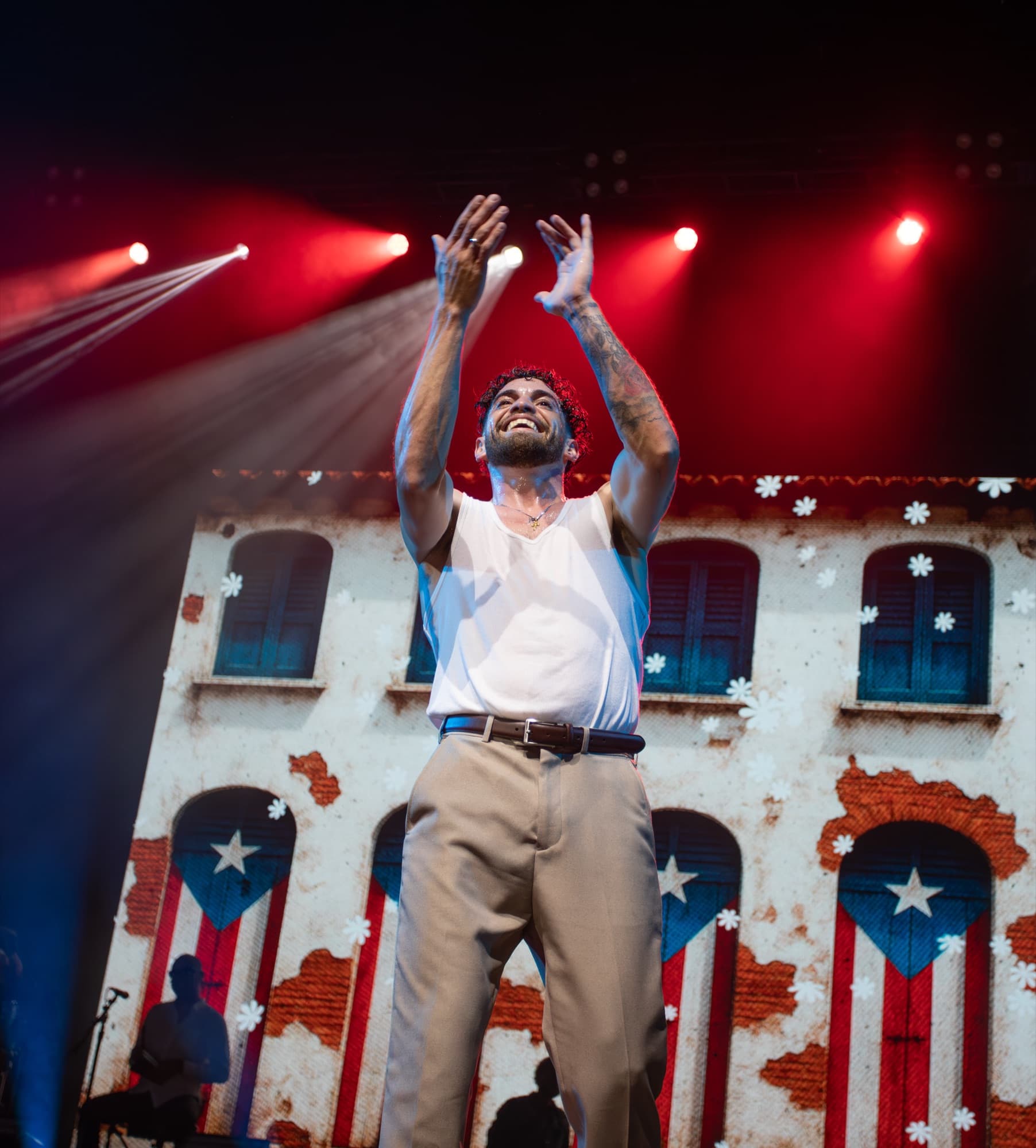 Artist in a white tank raising his fist before Old San Juan visuals
