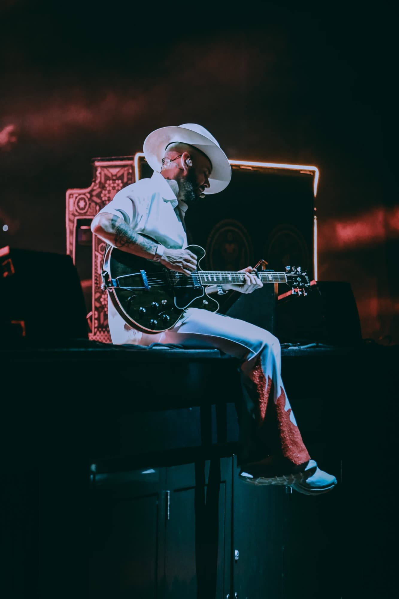 Jesse seated with his guitar in a pool of light