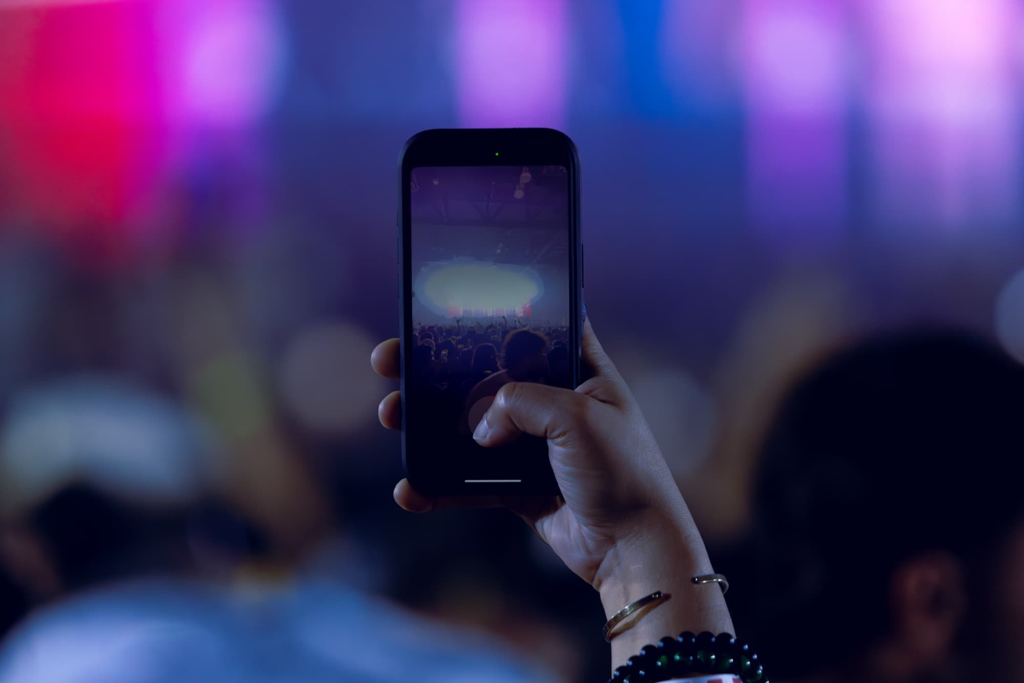 Fan filming the show on a phone held above the crowd