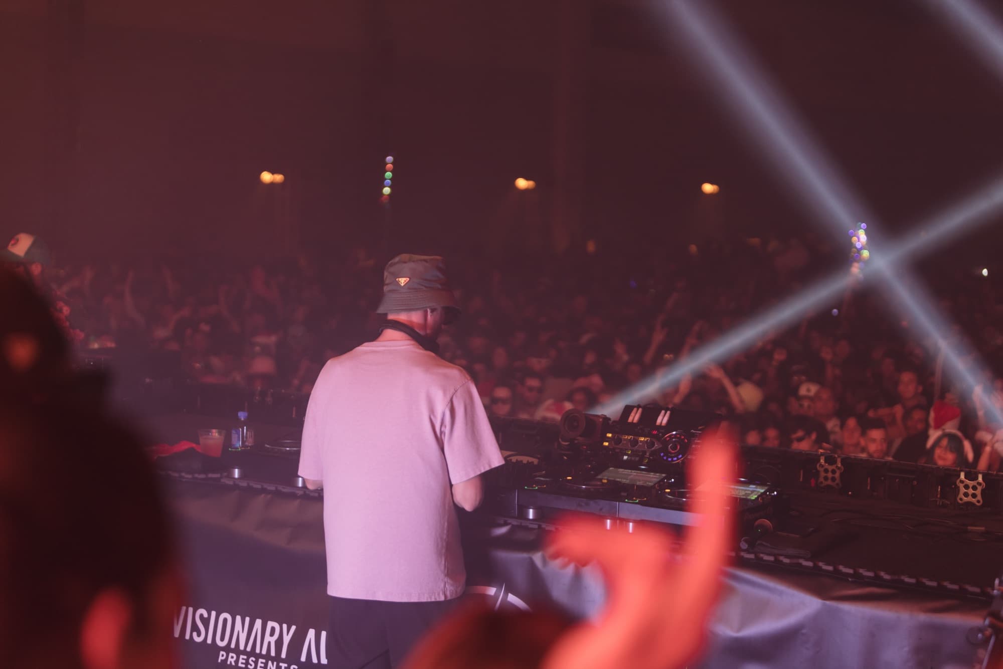 DJ from behind facing the crowd through white lasers