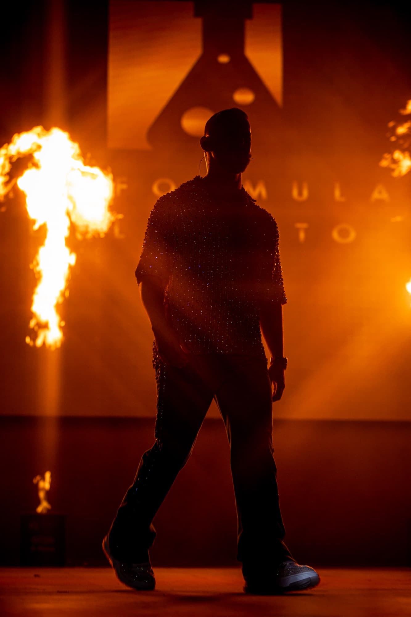 Elías Valentín silhouetted against flames and giant screen letters