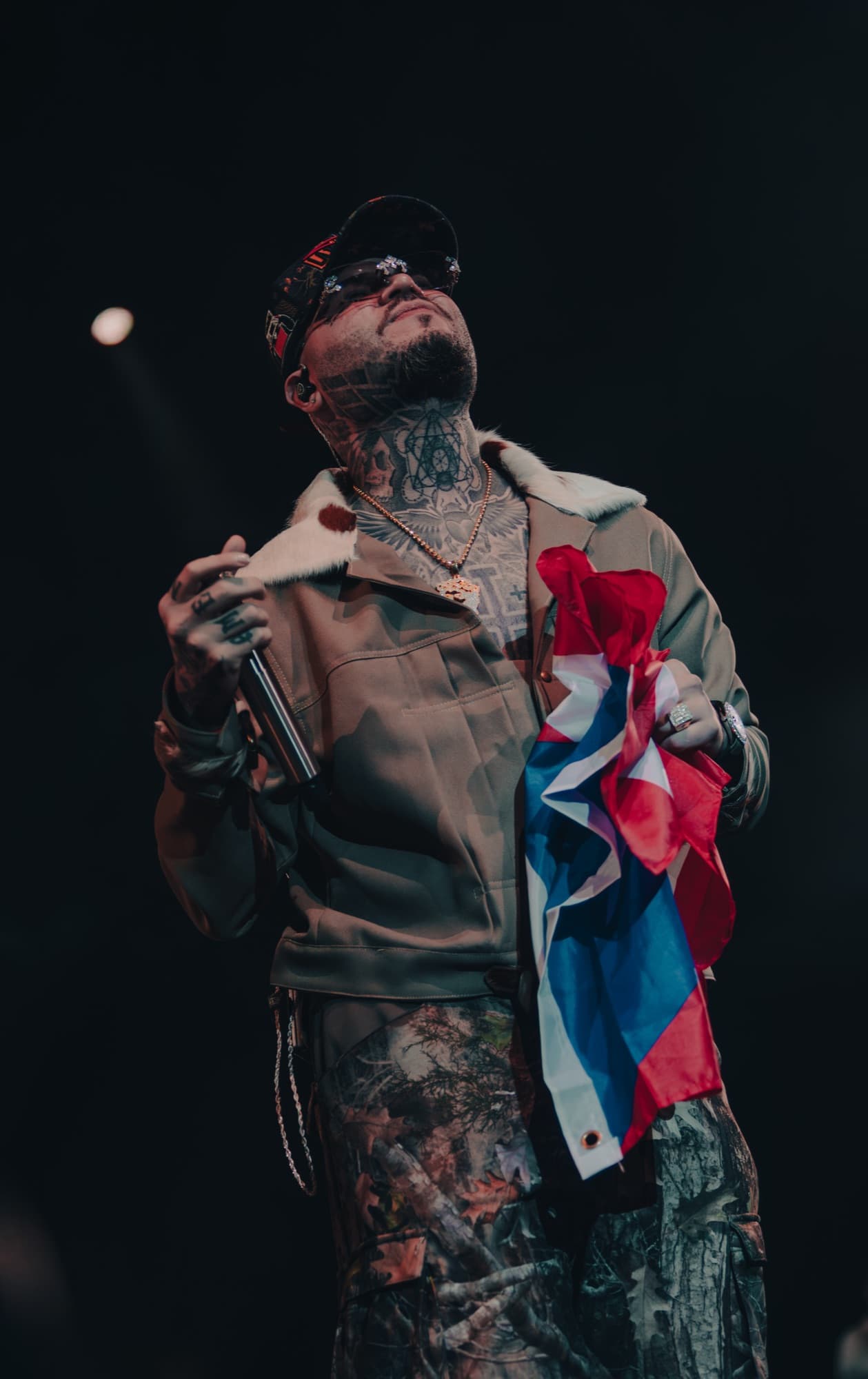 Tattooed artist holding the Puerto Rican flag at the mic