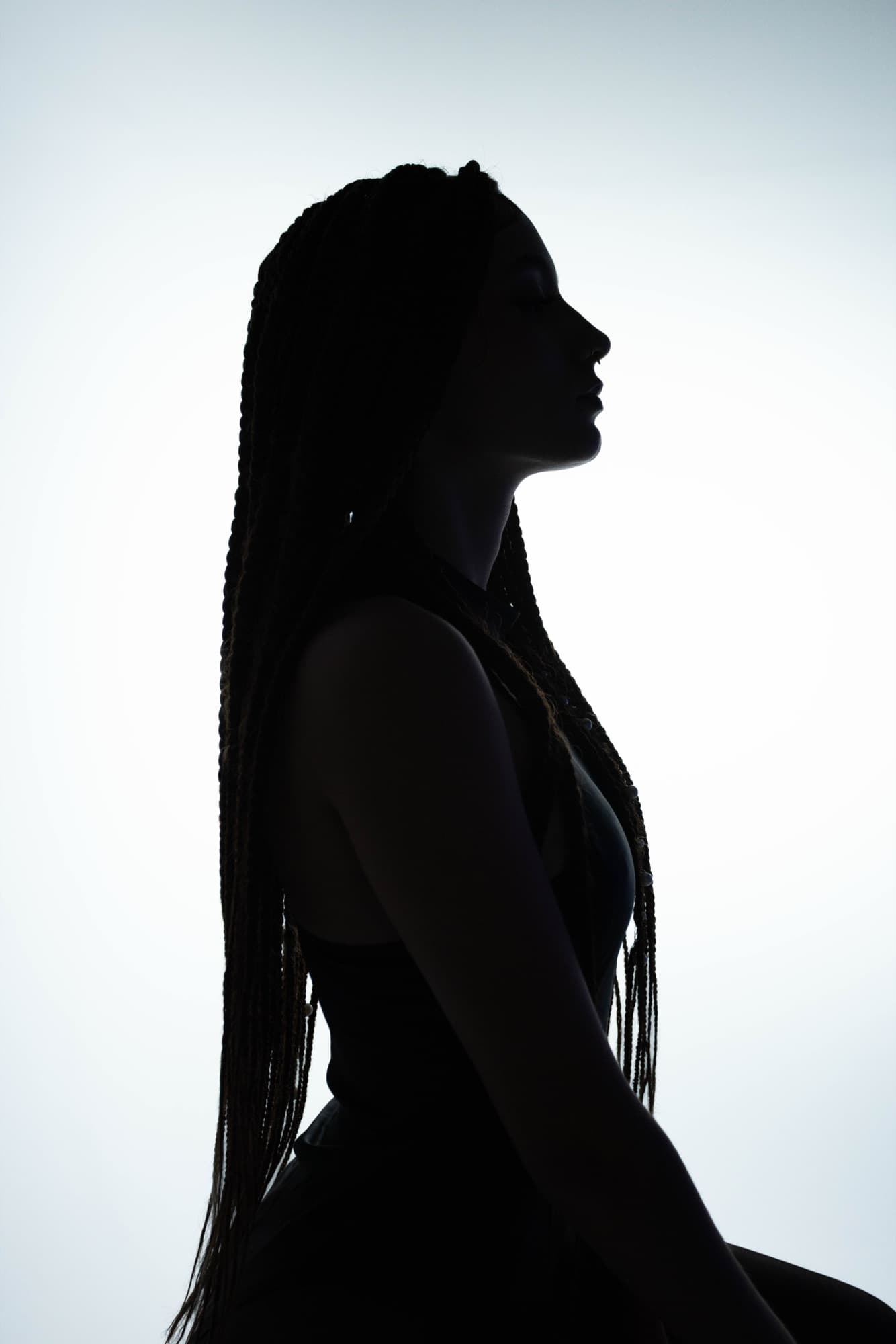 Backlit silhouette of a woman with long braids in profile
